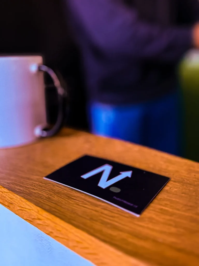 Visitekaartje met het beeldmerk van Nuzichtbaar op een houten tafel